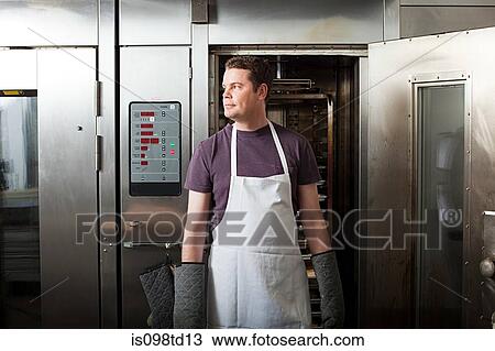 Male chef standing in front of oven View Large Photo Image Stock Image - Male chef standing in front of oven. Fotosearch