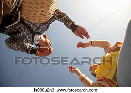 Low angle view of couple reaching for each other View Large Photo Image Stock Image - Low angle view of couple reaching for each other. Fotosearch