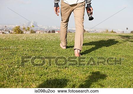 Picture - Man walking in field with video camera. Fotosearch