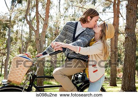 Stock Image - Young couple kissing on bicycle. Fotosearch