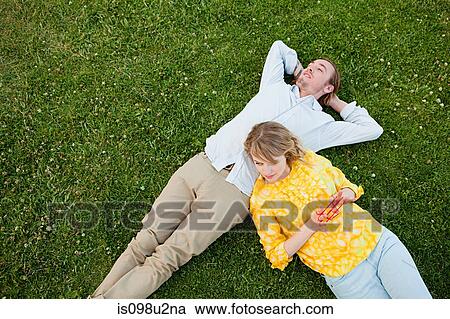 Young couple lying on grass View Large Photo Image Stock Image - Young couple lying on grass. Fotosearch
