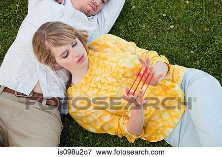 Stock Photo - Young couple outdoors, woman playing with string. Fotosearch
