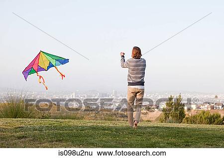 Young man flying a kite View Large Photo Image Stock Photograph - Young man flying a kite. Fotosearch