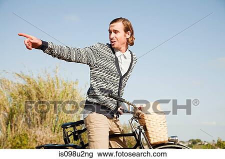 Young man on bicycle, pointing View Large Photo Image Stock Image - Young man on bicycle, pointing. Fotosearch