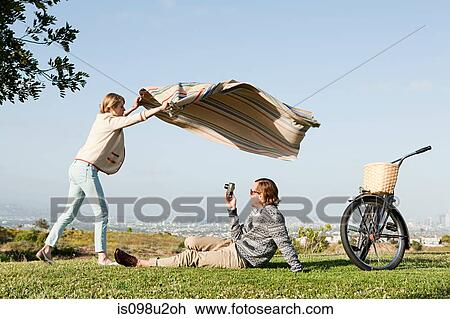 Young man photographing girlfriend as she shakes out a blanket View Large Photo Image Stock Image - Young man photographing girlfriend as she shakes out a blanket. Fotosearch