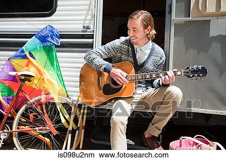 Young man playing guitar by caravan View Large Photo Image Picture - Young man playing guitar by caravan. Fotosearch