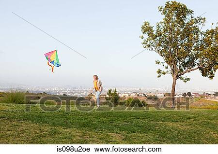 Young woman flying a kite in a field View Large Photo Image Stock Image - Young woman flying a kite in a field. Fotosearch