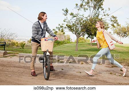 Stock Photography - Young woman running to boyfriend on bike. Fotosearch