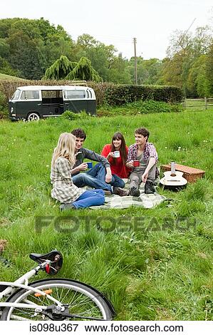 Friends sitting in field by camper van View Large Photo Image Stock Photo - Friends sitting in field by camper van. Fotosearch