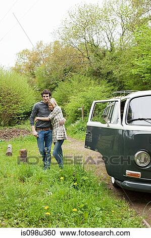 Stock Image - Young couple by camper van. Fotosearch