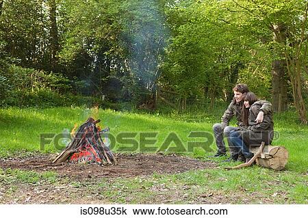Stock Image - Young couple by campfire. Fotosearch