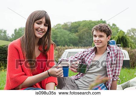 Stock Photograph - Young couple in field with cups. Fotosearch