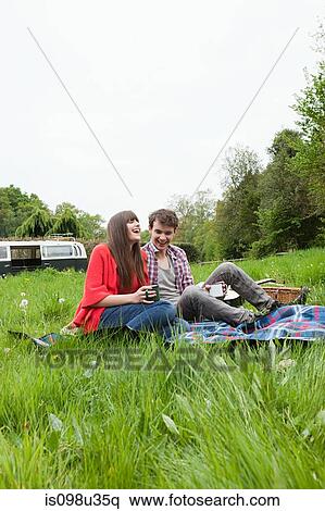 Stock Photography - Young couple on blanket in a field. Fotosearch