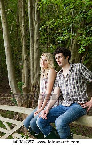 Young couple sitting on gate View Large Photo Image Stock Photo - Young couple sitting on gate. Fotosearch