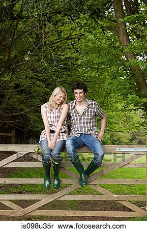Young couple sitting on gate View Large Photo Image Stock Photography - Young couple sitting on gate. Fotosearch