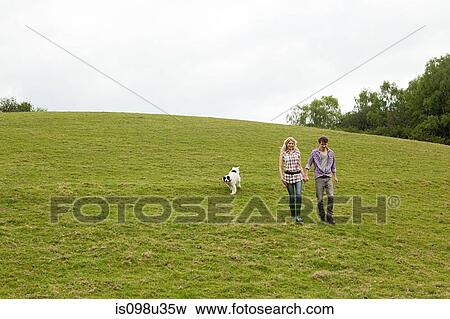 Young couple walking down hill with dog View Large Photo Image Stock Photo - Young couple walking down hill with dog. Fotosearch