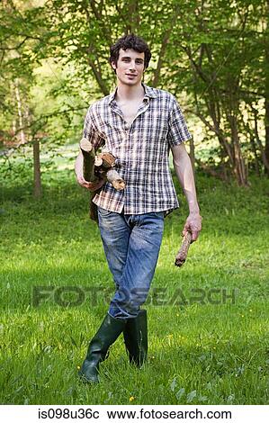 Stock Image - Young man holding logs. Fotosearch