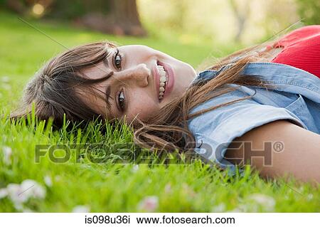 Young woman lying on grass View Large Photo Image Stock Image - Young woman lying on grass. Fotosearch