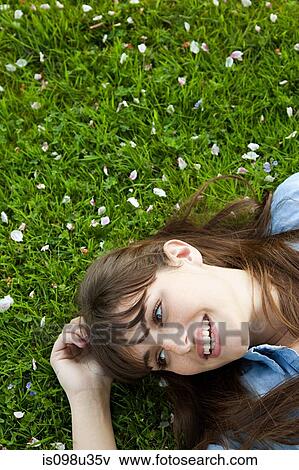 Stock Photo - Young woman lying on grass. Fotosearch