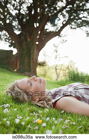 Young woman lying on grass with eyes closed View Large Photo Image Stock Image - Young woman lying on grass with eyes closed. Fotosearch