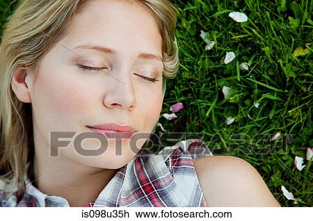 Young woman lying on grass with eyes closed View Large Photo Image Stock Image - Young woman lying on grass with eyes closed. Fotosearch