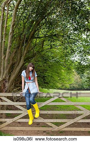 Young woman sitting on gate View Large Photo Image Stock Image - Young woman sitting on gate. Fotosearch