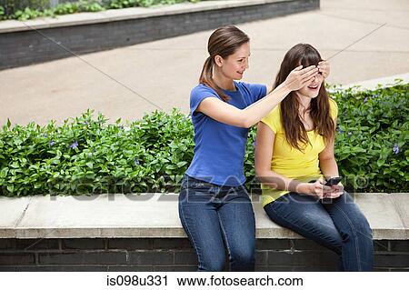 Girl covering friend's eyes View Large Photo Image Stock Image - Girl covering friend's eyes. Fotosearch