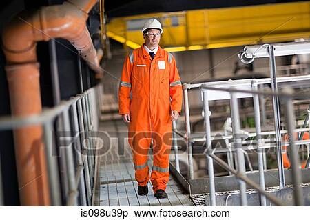 Stock Photography - Engineer walking along walkway in factory. Fotosearch