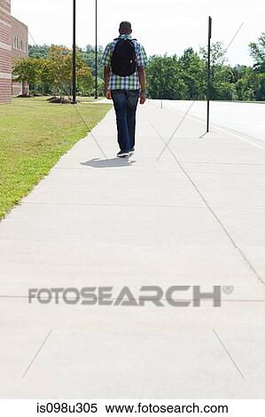 Male high school student walking along pavement View Large Photo Image Stock Photography - Male high school student walking along pavement. Fotosearch