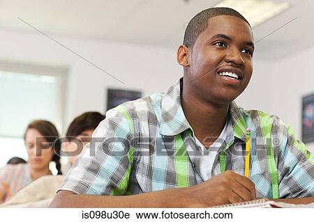 Stock Image - Male high school student working in classroom. Fotosearch