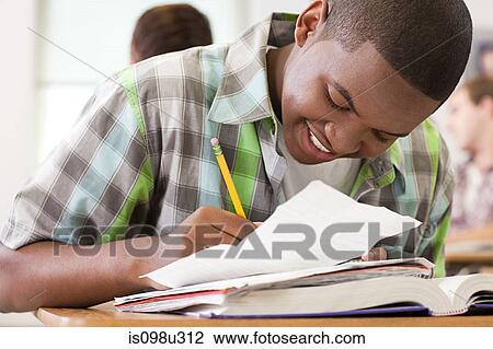 Stock Image - Male high school student working in classroom. Fotosearch
