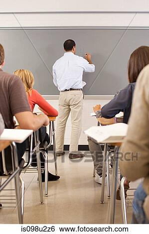 Stock Photograph - High school teacher using white board in classroom. Fotosearch