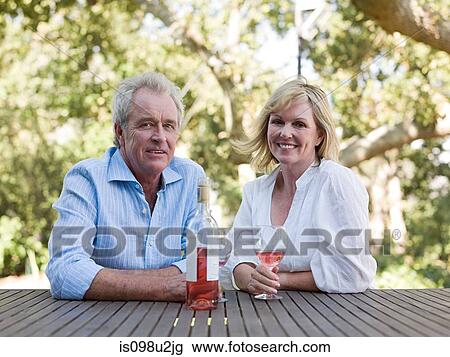 Stock Image - Mature couple outdoors with wine. Fotosearch
