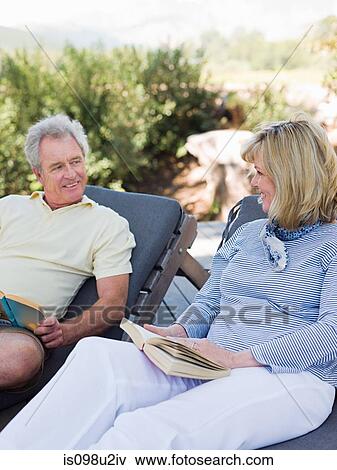 Mature couple relaxing on loungers with books View Large Photo Image Stock Photo - Mature couple relaxing on loungers with books. Fotosearch