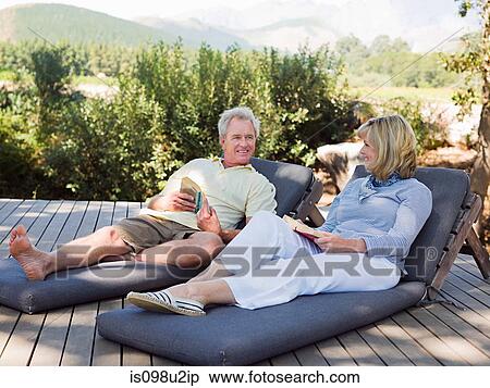 Mature couple relaxing on loungers with books View Large Photo Image Stock Photography - Mature couple relaxing on loungers with books. Fotosearch