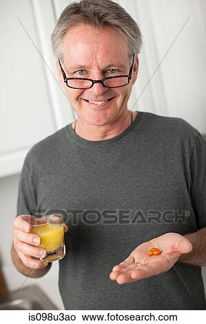 Man with vitamins and orange juice View Large Photo Image Picture - Man with vitamins and orange juice. Fotosearch