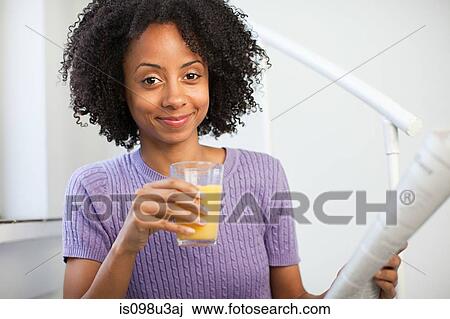 Stock Image - Woman with glass of juice and newspaper. Fotosearch