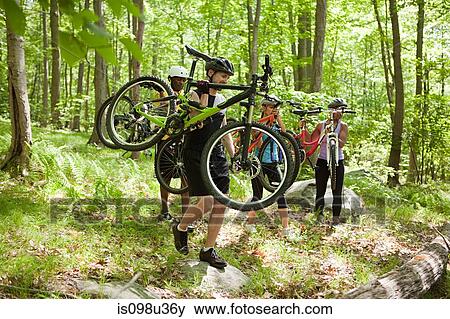 Cyclists carrying bikes in forest View Large Photo Image Stock Photo - Cyclists carrying bikes in forest. Fotosearch
