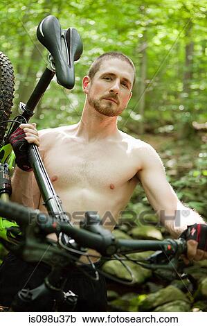 Male cyclist carrying bike in forest View Large Photo Image Stock Image - Male cyclist carrying bike in forest. Fotosearch