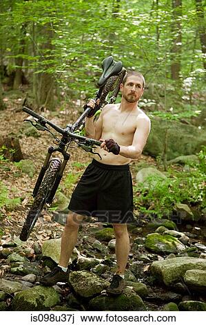 Male cyclist carrying bike in forest View Large Photo Image Stock Image - Male cyclist carrying bike in forest. Fotosearch