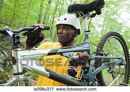 Male cyclist carrying bike in forest View Large Photo Image Stock Photo - Male cyclist carrying bike in forest. Fotosearch