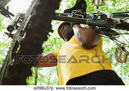 Male cyclist carrying bike in forest View Large Photo Image Stock Photography - Male cyclist carrying bike in forest. Fotosearch
