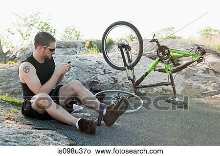 Male cyclist fixing punctured tyre View Large Photo Image Picture - Male cyclist fixing punctured tyre. Fotosearch