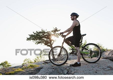 Stock Image - Male cyclist on rocks. Fotosearch