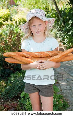 Stock Image - Girl in sunhat holding baguettes. Fotosearch