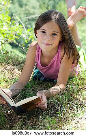 Girls lying on front with book View Large Photo Image Stock Photo - Girls lying on front with book. Fotosearch