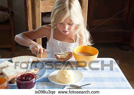 Stock Image - Girls spreading butter on bread. Fotosearch