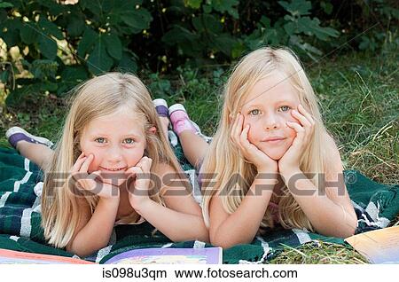 Two girls lying on blanket with books View Large Photo Image Picture - Two girls lying on blanket with books. Fotosearch