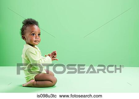 Baby boy kneeling against green background View Large Photo Image Stock Image - Baby boy kneeling against green background. Fotosearch