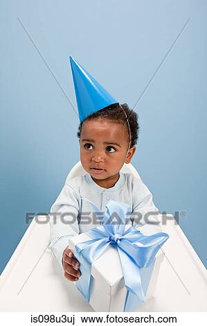Stock Image - Baby boy sitting in highchair with gift box. Fotosearch